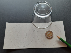 Schritt 1:
Mit dem Zirkel oder einem runden Gegenstand zwei gleichgroße Kreise auf eine Pappe zeichnen.
In die Mitte jeweils einen kleineren Kreis zeichnen.